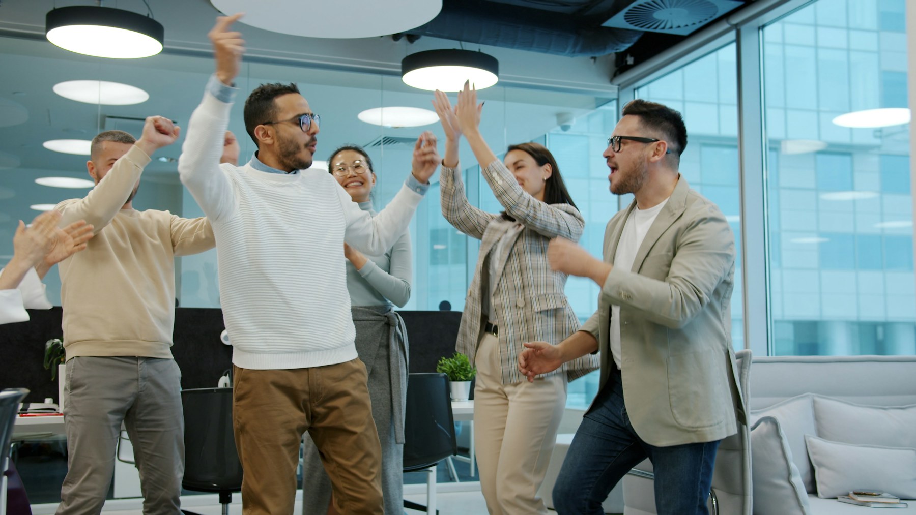 Colleagues cheering and high-fiving during a team social