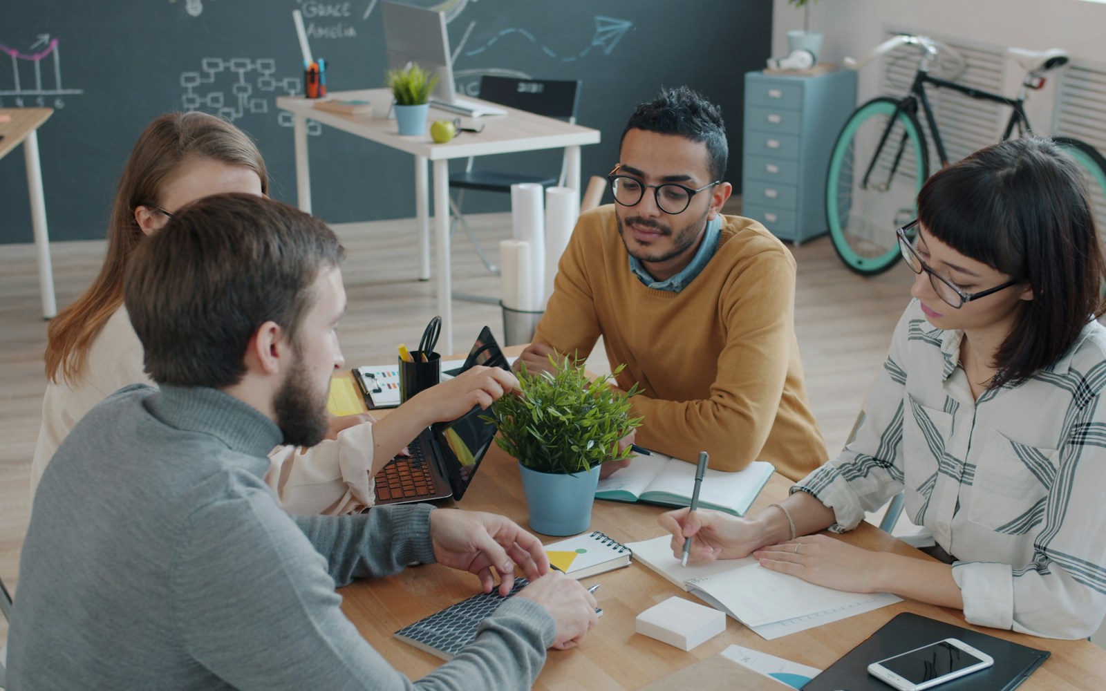 Four colleagues collaborating around a table in a small office team