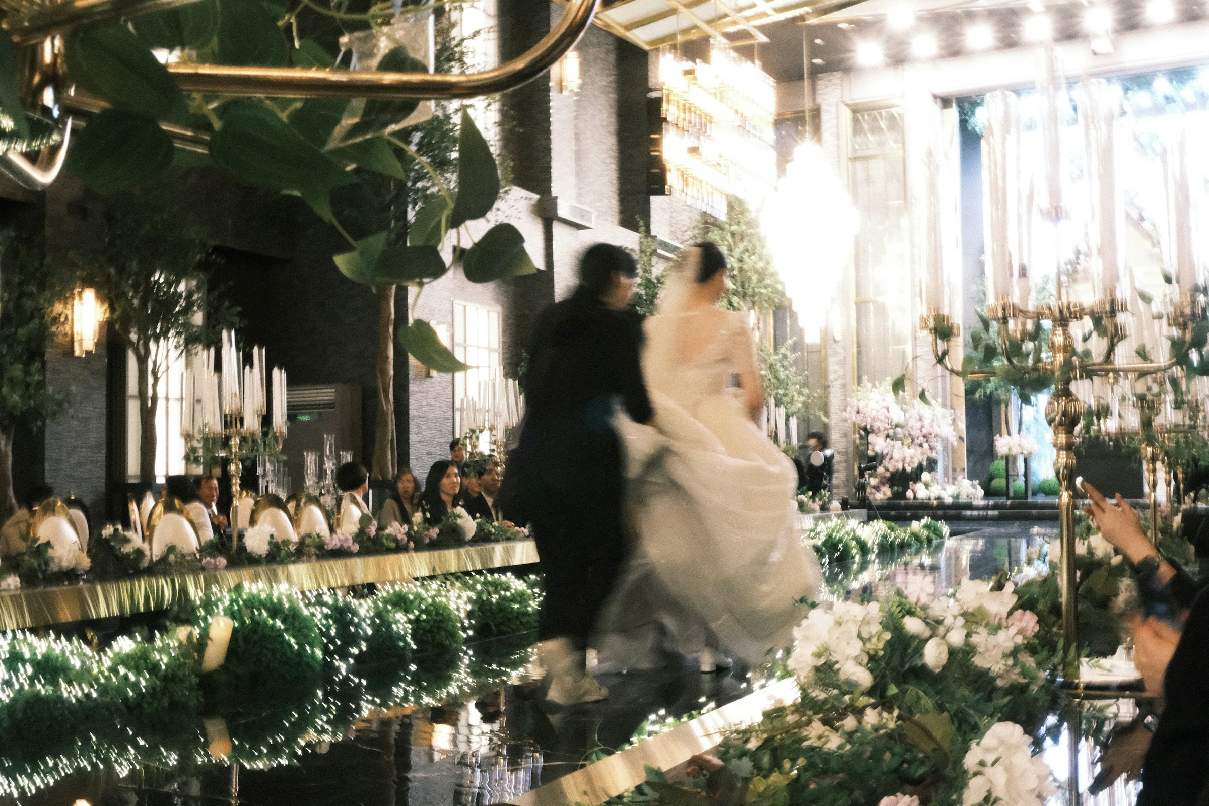 A bride and groom walking down the aisle at their wedding reception